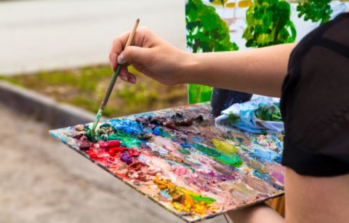 Persona pintando con un mezclador y pincel al aire libre