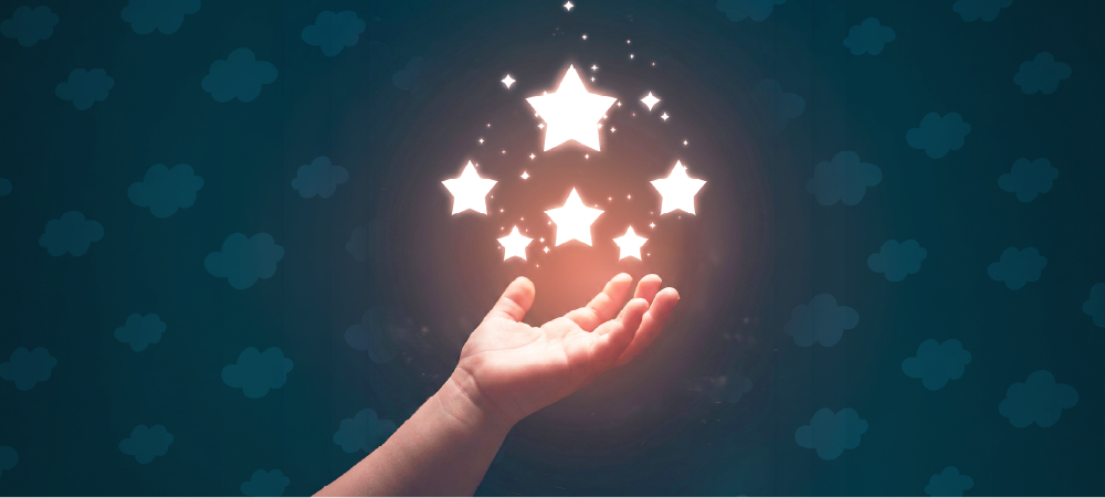 Mano de un niño extendida hacia un grupo de estrellas luminosas, simbolizando el recuerdo, el amor y el homenaje a los niños que permanecen en el corazón de sus familias.