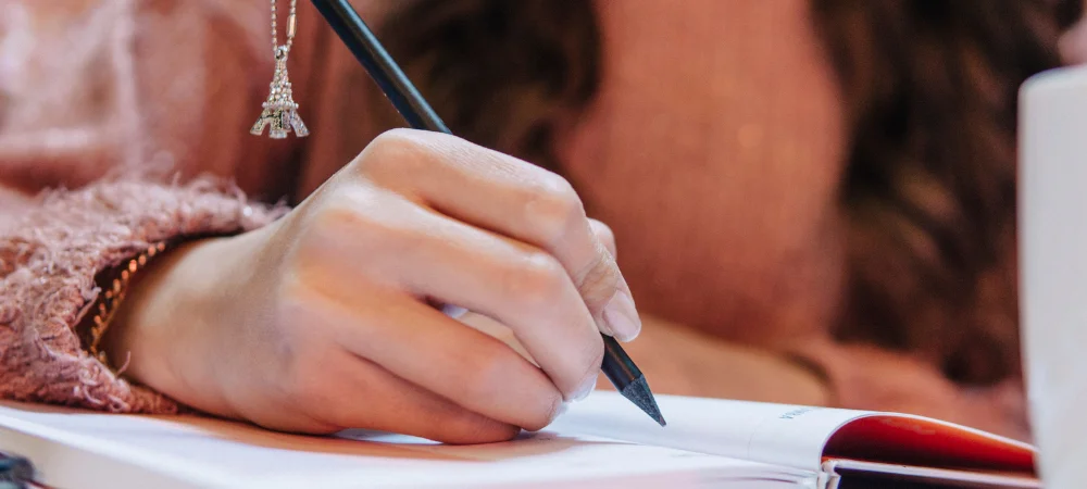 Mujer escribiendo en un cuaderno durante un momento de reflexión personal y conexión con sus emociones.