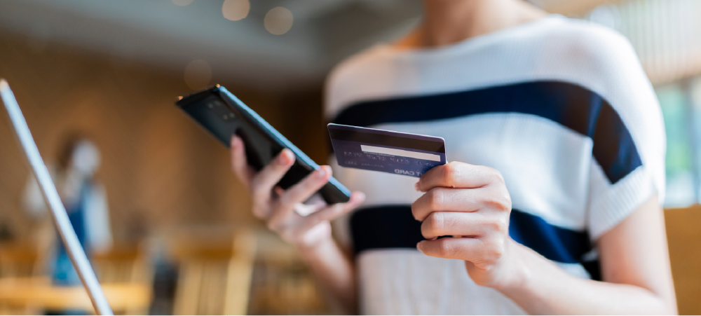 Mujer realizando un pago en línea con tarjeta de crédito desde su celular